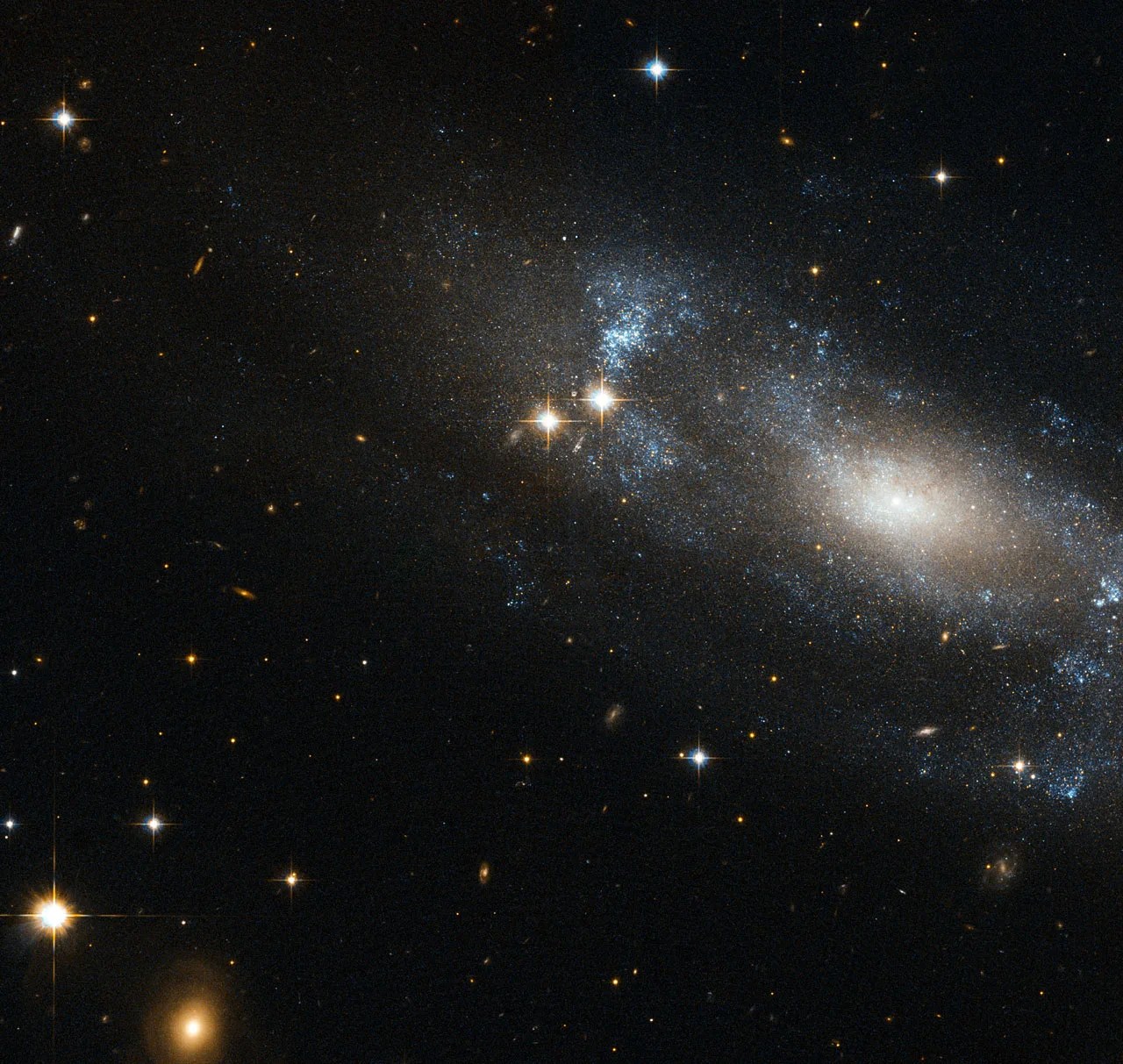 an assymetric galaxy with swirls of bluish stars and two bright flares