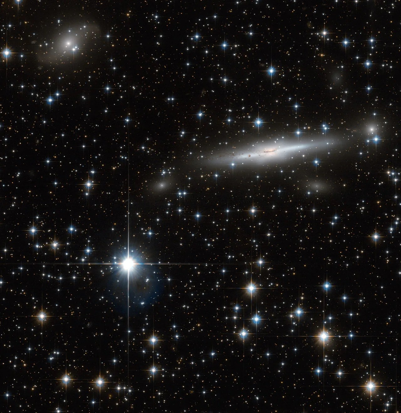 a spiral galaxy streaks across the upper right, flanked by a bright star lower left beneath a hazy smaller galaxy
