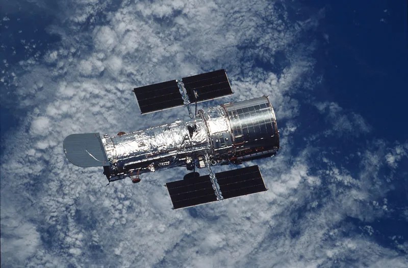 hubble floating against a backdrop of earth