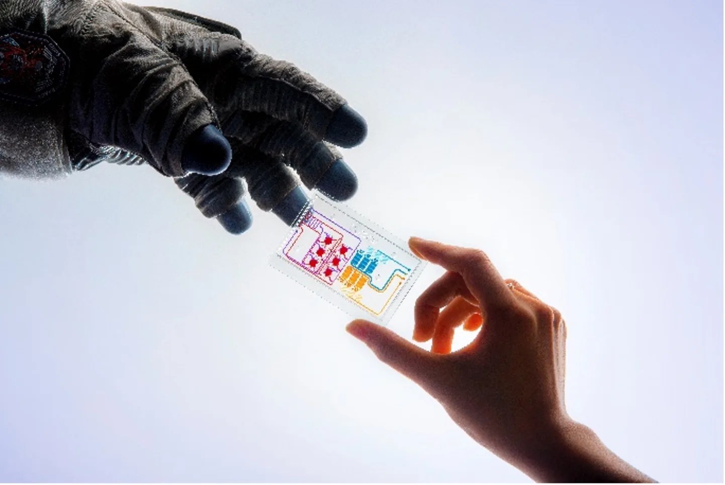 Photograph of a hand holding a colorized chip being handed to a gloved hand.