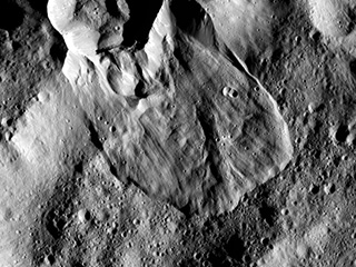 Orbiting Ceres, a section of the wall of the crater at the top of the picture collapsed, allowing material to flow downhill into the larger Ghanan Crater, only a portion of which is shown.